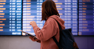 Mujer viendo hacia las pantallas digital signage de un aeropuerto.