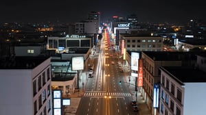 Vista nocturna de una avenida urbana larga y recta, iluminada por faroles y el tránsito de autos. Edificios comerciales a ambos lados muestran anuncios luminosos, creando un corredor de luces en la ciudad.