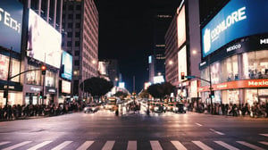Avenida urbana de noche con tráfico, peatones y grandes pantallas publicitarias iluminando edificios comerciales.